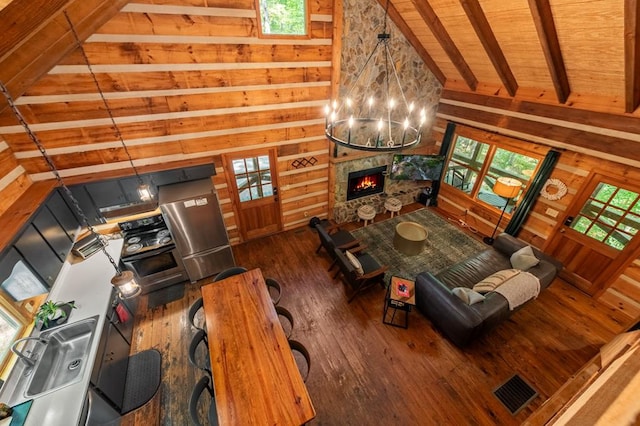 living room with a stone fireplace, wood walls, wood ceiling, visible vents, and dark wood-style floors