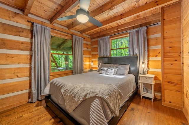 bedroom featuring beamed ceiling, hardwood / wood-style flooring, wood ceiling, and wooden walls