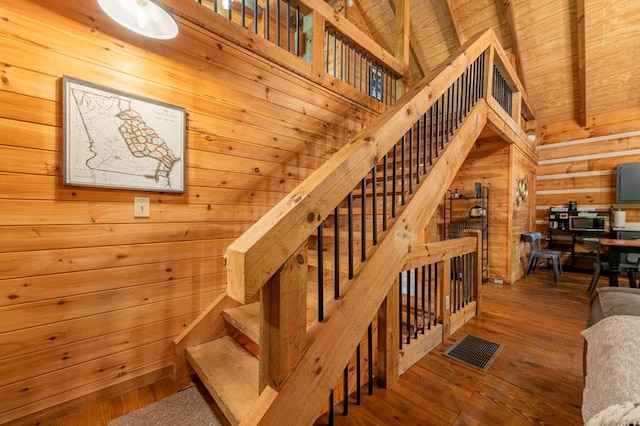 stairs with visible vents, wood ceiling, wooden walls, wood finished floors, and beamed ceiling