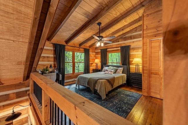 bedroom with lofted ceiling with beams, ceiling fan, wood walls, wooden ceiling, and hardwood / wood-style flooring