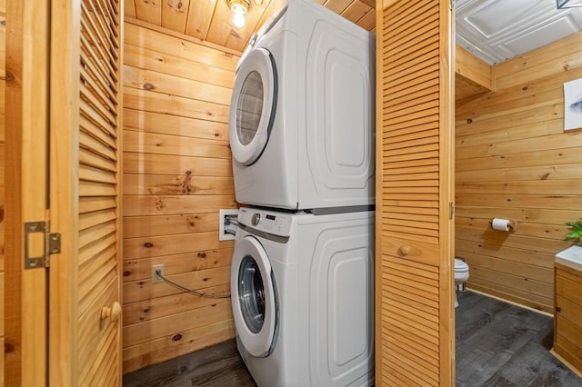 laundry room with wooden walls, dark wood-style flooring, and stacked washer / drying machine