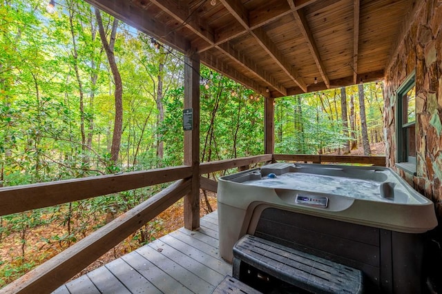 wooden deck featuring a forest view and a hot tub