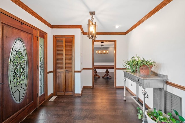 entrance foyer with crown molding, dark wood-type flooring, and a chandelier