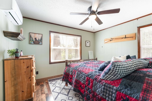 bedroom featuring crown molding, a wall unit AC, wood finished floors, and baseboards