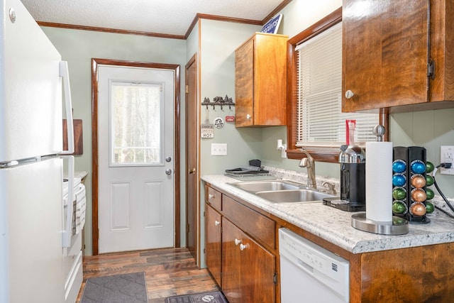 kitchen with white appliances, light countertops, crown molding, a sink, and wood finished floors