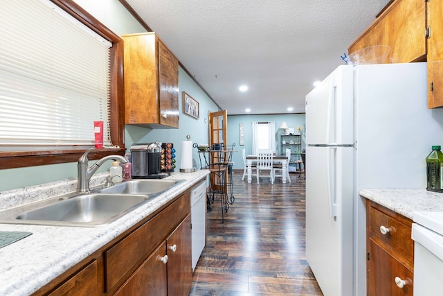 kitchen with white appliances, light countertops, brown cabinets, dark wood finished floors, and a sink