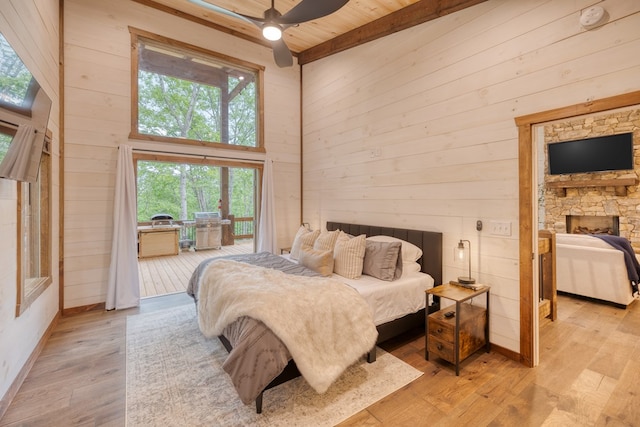 bedroom with light wood-type flooring, ceiling fan, wooden walls, high vaulted ceiling, and beamed ceiling