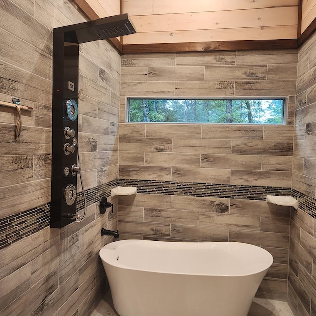 bathroom featuring wooden walls, a tub to relax in, and a healthy amount of sunlight