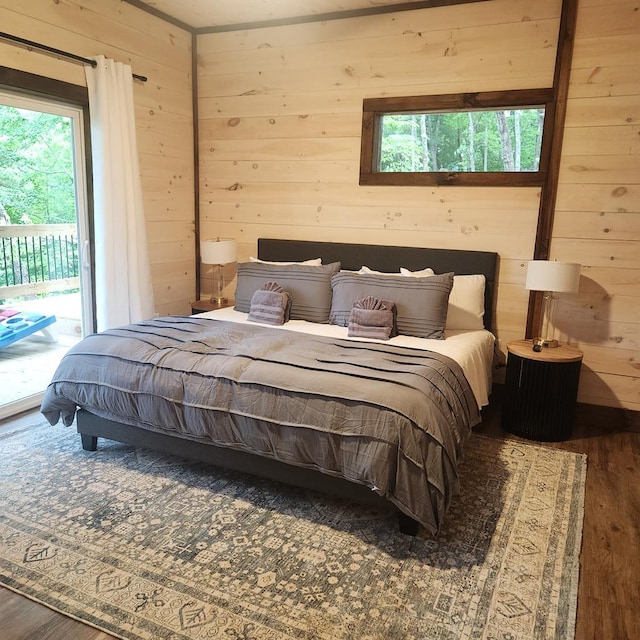 bedroom with access to outside, wood walls, and hardwood / wood-style flooring