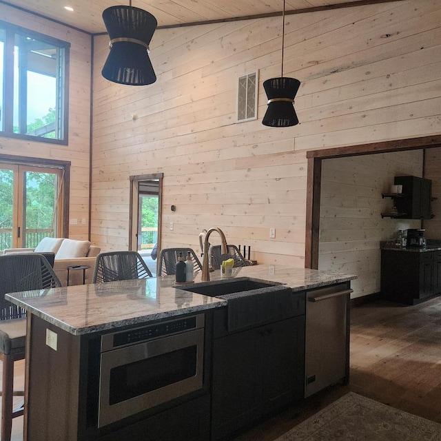 kitchen featuring light stone counters, plenty of natural light, stainless steel dishwasher, and sink