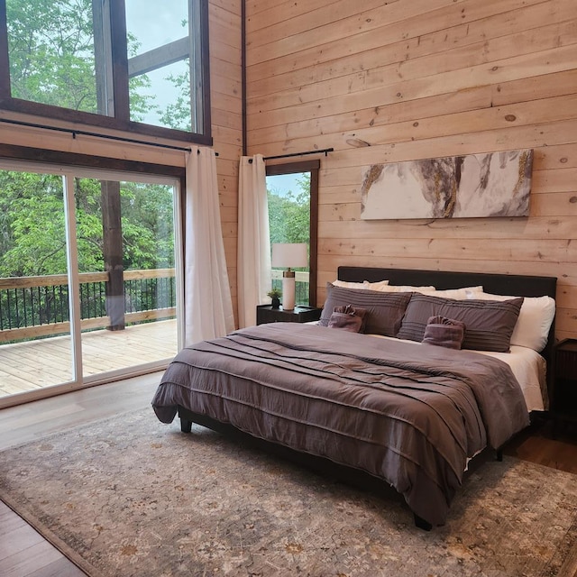 bedroom featuring hardwood / wood-style floors, access to outside, and wooden walls