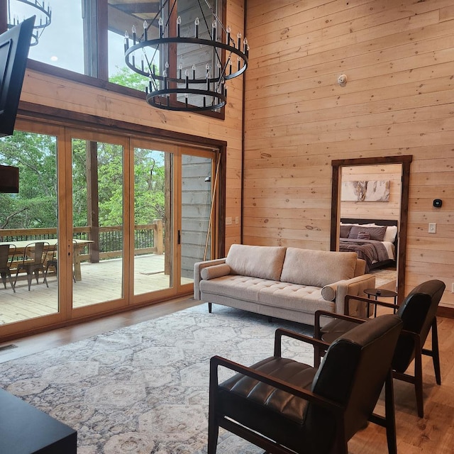 living room featuring hardwood / wood-style floors, wood walls, a wealth of natural light, and an inviting chandelier