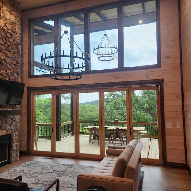 doorway to outside with french doors, wooden walls, hardwood / wood-style flooring, an inviting chandelier, and a fireplace