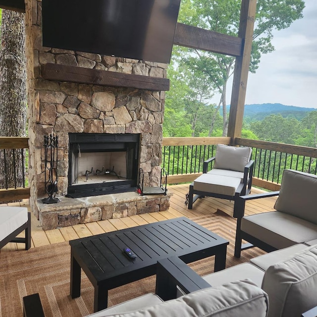 wooden terrace with an outdoor living space with a fireplace