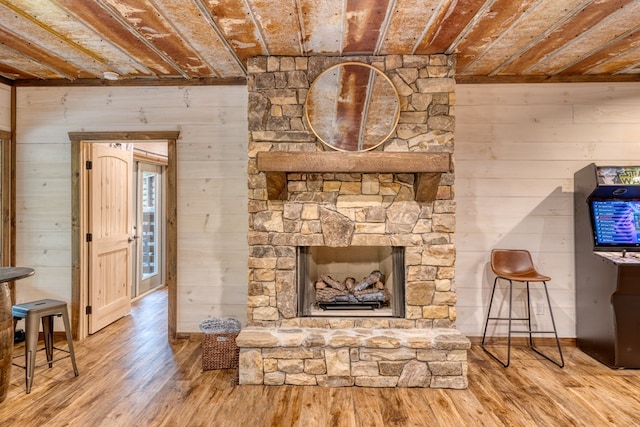 living room featuring a stone fireplace, wood walls, hardwood / wood-style floors, and wood ceiling