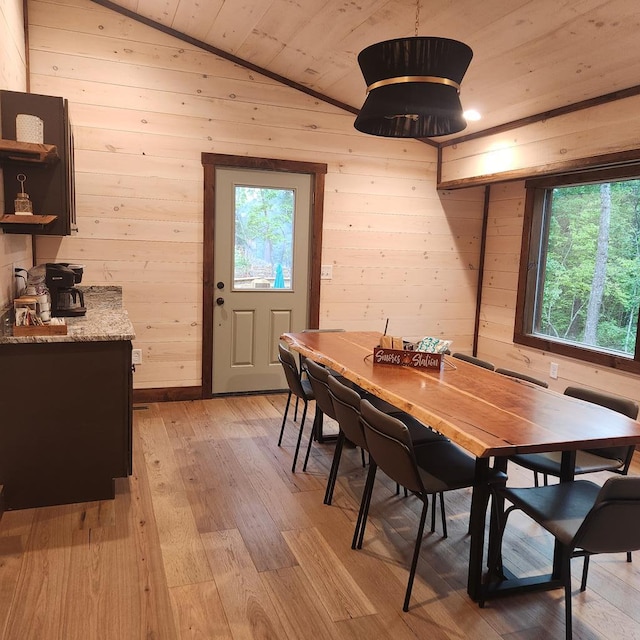 dining area with light wood-type flooring, lofted ceiling, wooden walls, and wooden ceiling