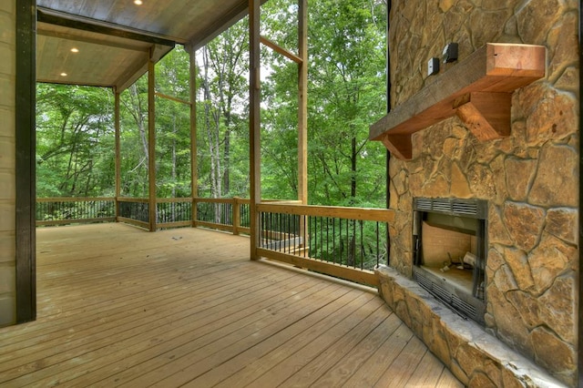 unfurnished sunroom with an outdoor stone fireplace and plenty of natural light