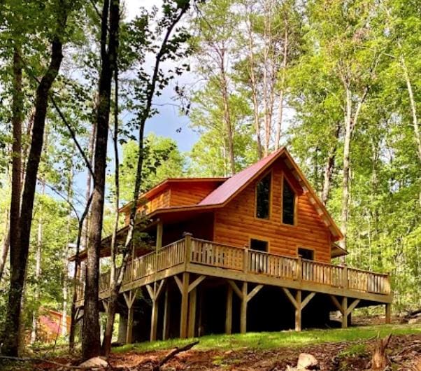 back of house featuring a forest view and a wooden deck