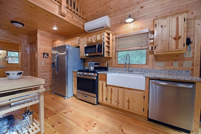 kitchen with light brown cabinetry, a wall mounted air conditioner, stainless steel appliances, and wooden walls