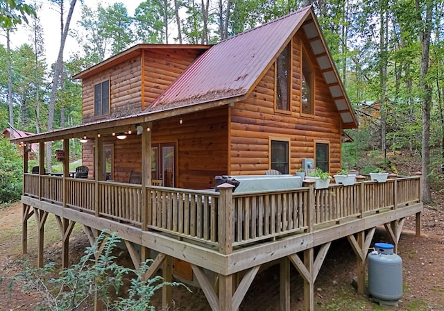 exterior space featuring log veneer siding, metal roof, and a wooden deck