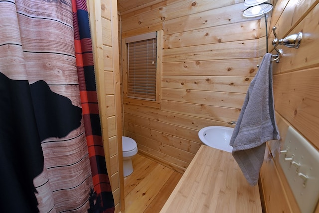 bathroom featuring vanity, wooden walls, wood finished floors, curtained shower, and toilet