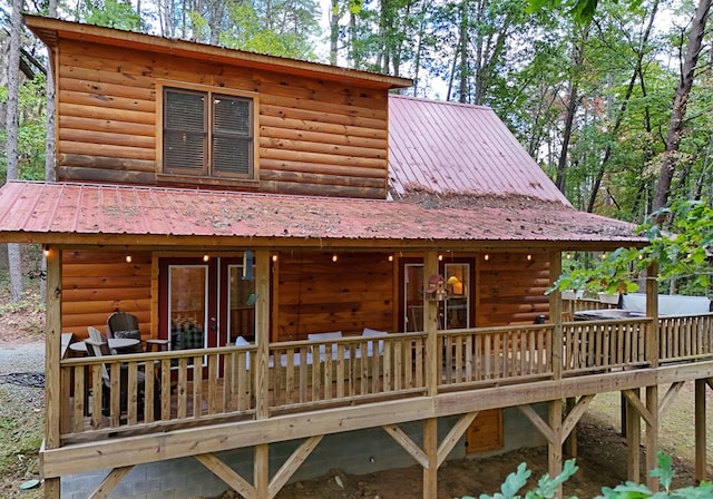 rear view of house with a deck, metal roof, and log veneer siding