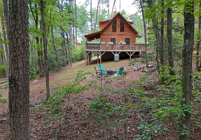 back of house featuring log veneer siding, a fire pit, and a deck