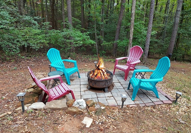 view of patio with a forest view and a fire pit