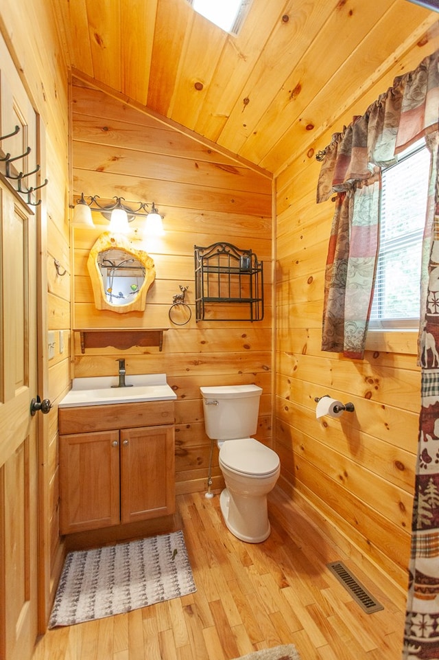 bathroom with vanity, toilet, wooden walls, and hardwood / wood-style flooring