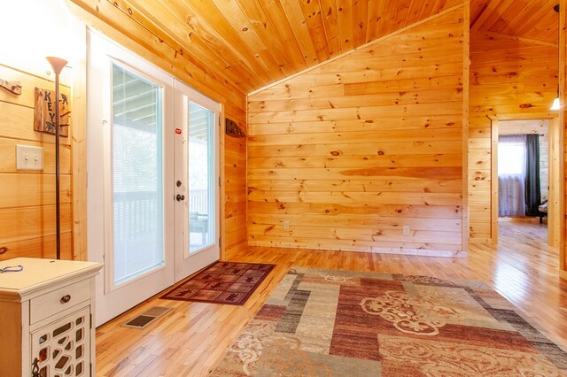 doorway to outside with wooden ceiling, wood walls, light wood-type flooring, and french doors