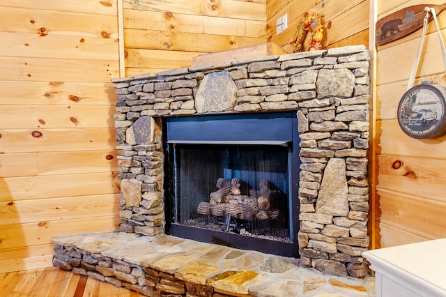 details with wood walls, a stone fireplace, and wood-type flooring