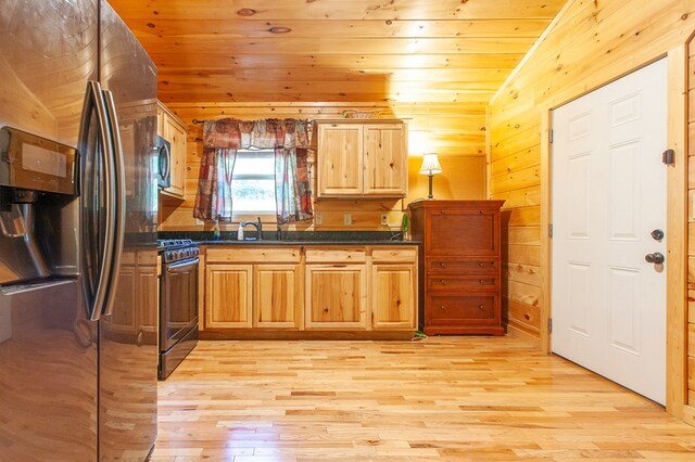 kitchen with wooden walls, light hardwood / wood-style flooring, gas range, stainless steel fridge with ice dispenser, and lofted ceiling