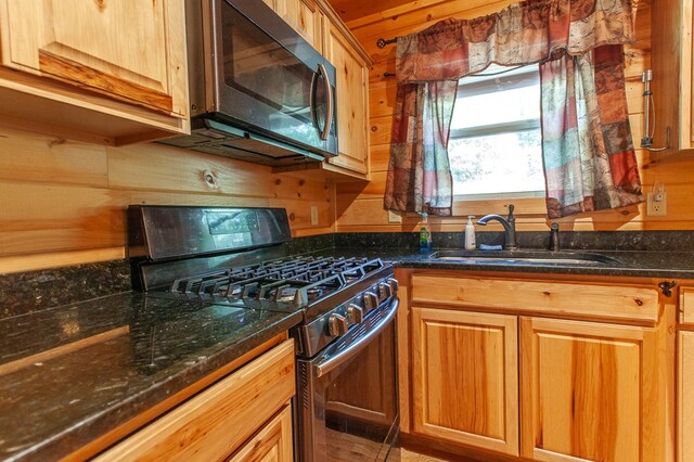 kitchen featuring black gas stove, dark stone countertops, and sink