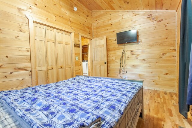 bedroom with wood walls, light hardwood / wood-style flooring, a closet, wood ceiling, and lofted ceiling