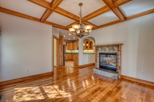 unfurnished living room with an inviting chandelier, coffered ceiling, and light wood-type flooring