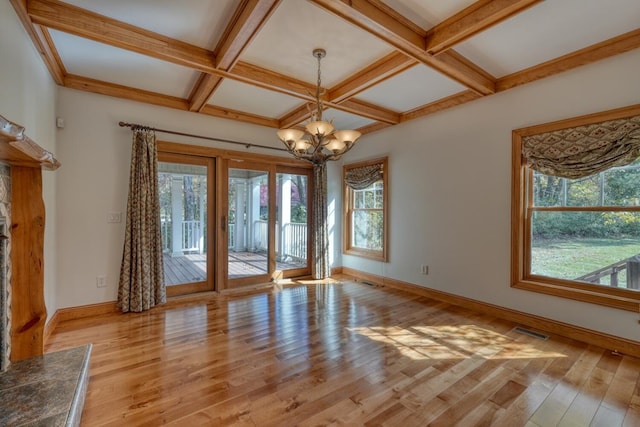 spare room with beam ceiling, light hardwood / wood-style floors, a notable chandelier, and coffered ceiling