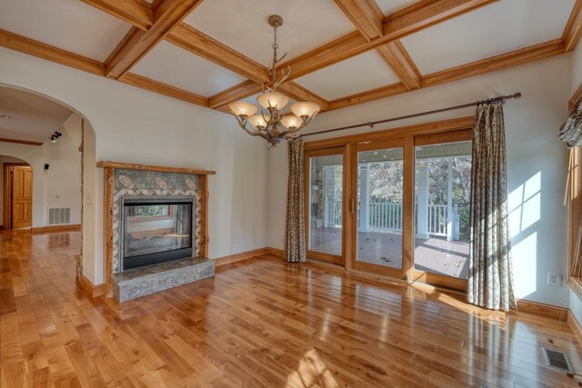 unfurnished living room featuring a tile fireplace, light hardwood / wood-style floors, an inviting chandelier, and coffered ceiling