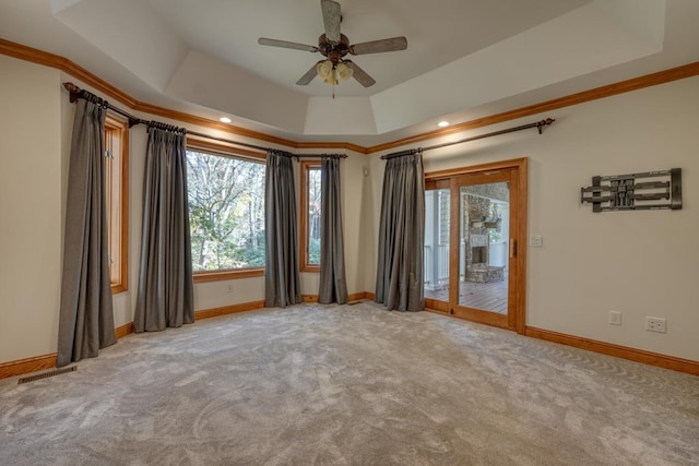 empty room featuring ornamental molding, a tray ceiling, and light colored carpet