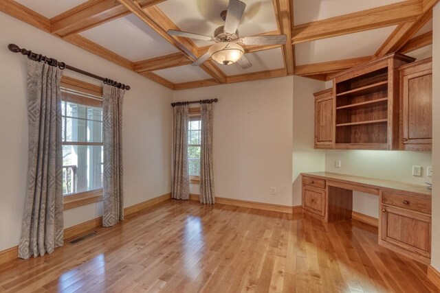 unfurnished office with light hardwood / wood-style flooring, built in desk, and coffered ceiling