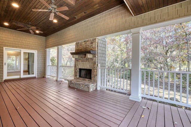 deck featuring an outdoor stone fireplace and ceiling fan