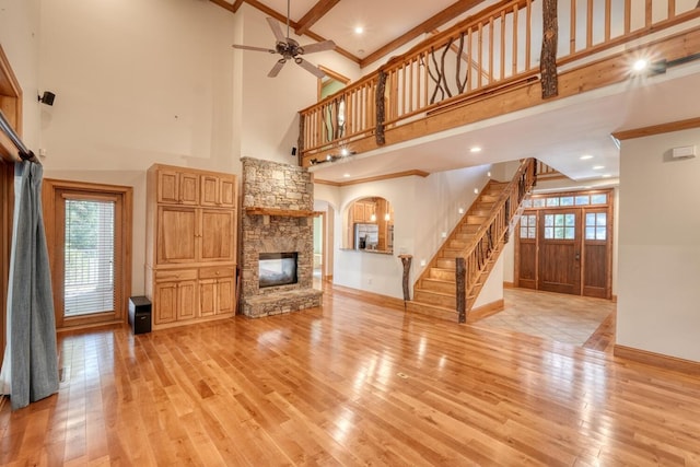 unfurnished living room with light hardwood / wood-style floors, beam ceiling, and a high ceiling