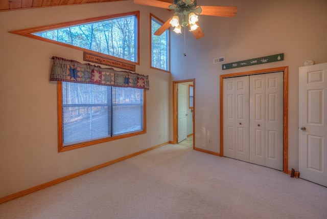 unfurnished bedroom with high vaulted ceiling, light carpet, ceiling fan, and a closet