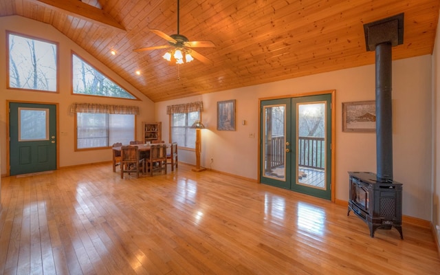 unfurnished dining area featuring french doors, high vaulted ceiling, wooden ceiling, a wood stove, and light hardwood / wood-style floors