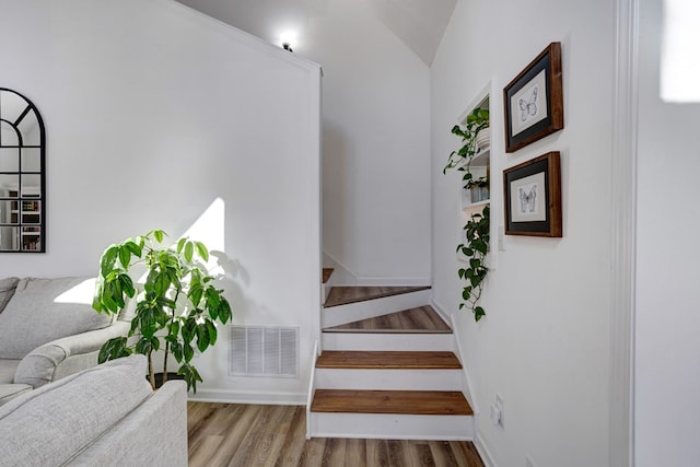 stairs featuring hardwood / wood-style flooring and lofted ceiling