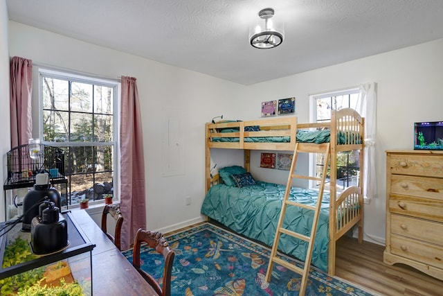 bedroom with multiple windows, hardwood / wood-style floors, and a textured ceiling