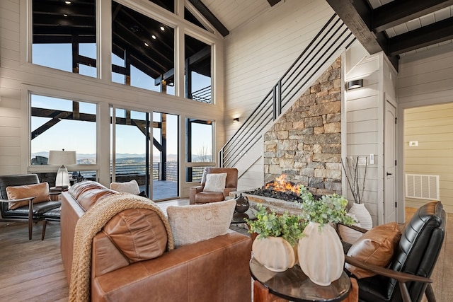 living room with beamed ceiling, hardwood / wood-style flooring, high vaulted ceiling, and wood walls