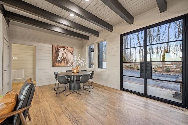 dining space featuring wood ceiling, wood walls, beamed ceiling, and light wood-type flooring