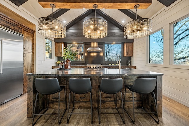 bar with a chandelier, stainless steel built in fridge, sink, and wood walls