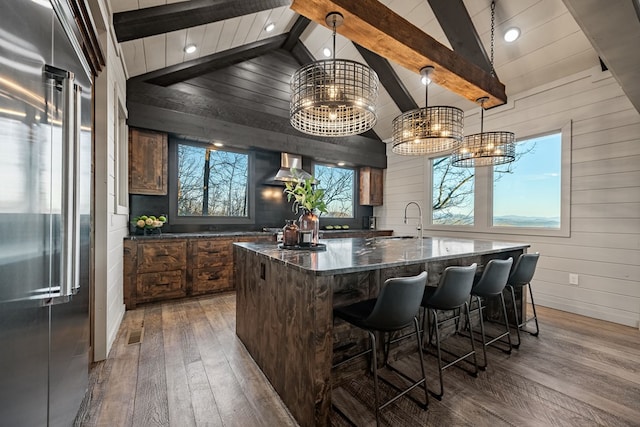 interior space featuring wood-type flooring, pendant lighting, high end fridge, and dark stone countertops