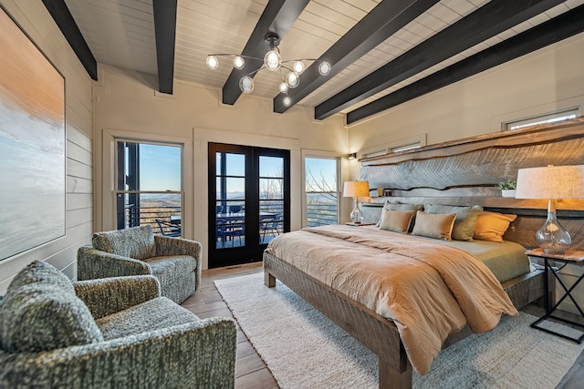 bedroom with french doors, light hardwood / wood-style floors, multiple windows, and beamed ceiling